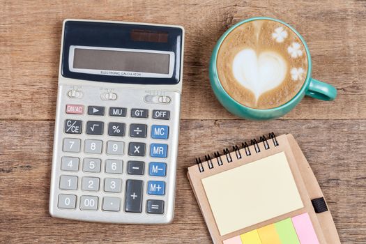 calculator and cup of coffee on wood 
