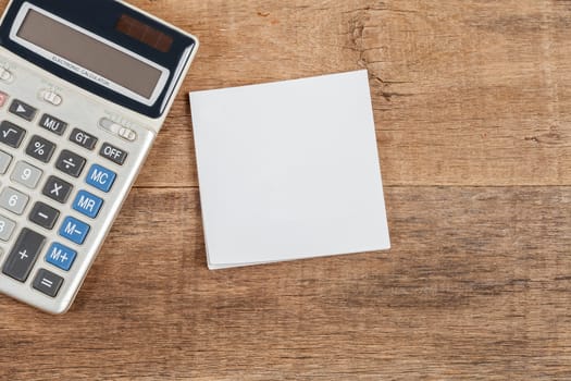 notebook showing empty page  and calculator on wooden desk