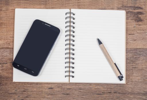 mobile phone and book note in vintage wooden desk