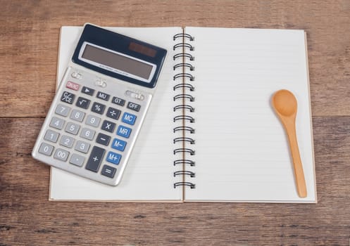 notebook showing empty page  and calculator on wooden 
desk