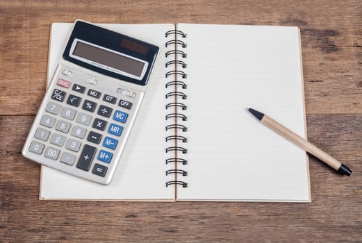 notebook showing empty page  and calculator on wooden 
desk