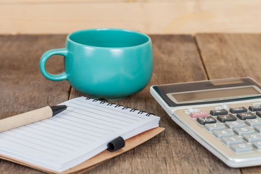 calculator, pen and cup of coffee on wood 