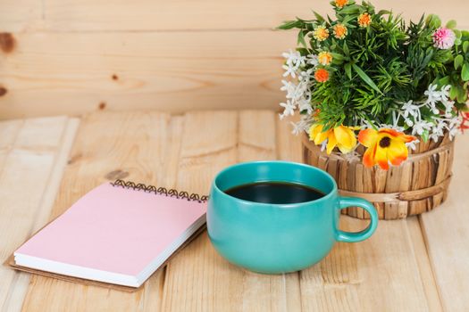 note book with cup and vase on wood table