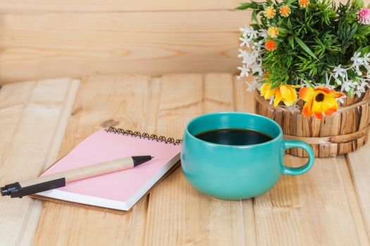 note book with cup and vase on wood table