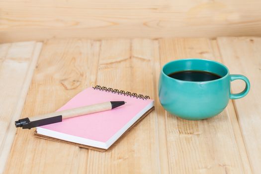 note book with cup and vase on wood table