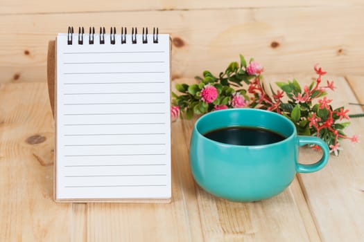 note book with cup and vase on wood table