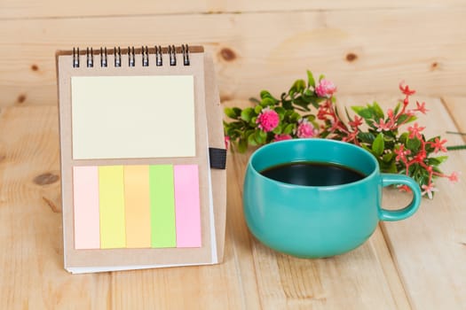 note book with cup and vase on wood table
