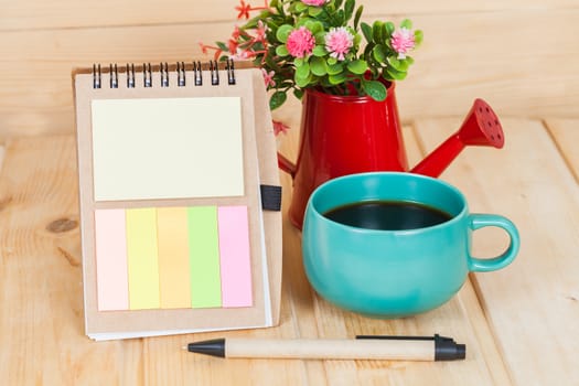 note book with cup and vase on wood table
