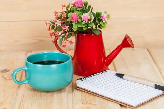 note book with cup and vase on wood table
