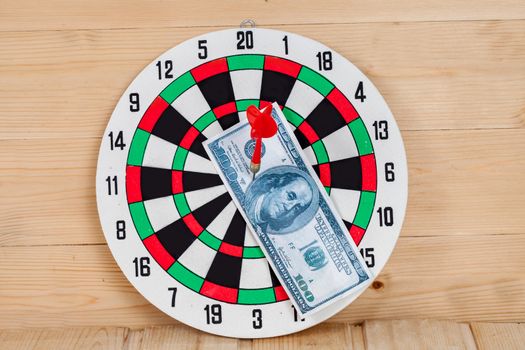 Dart arrow hitting in bullseye on dartboard with money