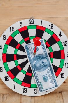 Dart arrow hitting in bullseye on dartboard with money
