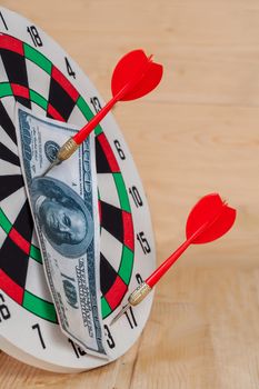 Dart arrow hitting in bullseye on dartboard with money