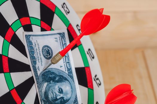 Dart arrow hitting in bullseye on dartboard with money