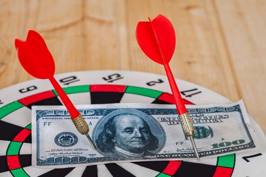 Dart arrow hitting in bullseye on dartboard with money