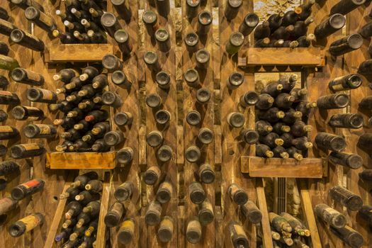 Many red wine bottles stacked on wooden racks