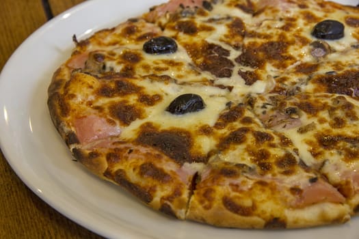 tasty pizza with mushrooms, cheese, olives and meat on the plate