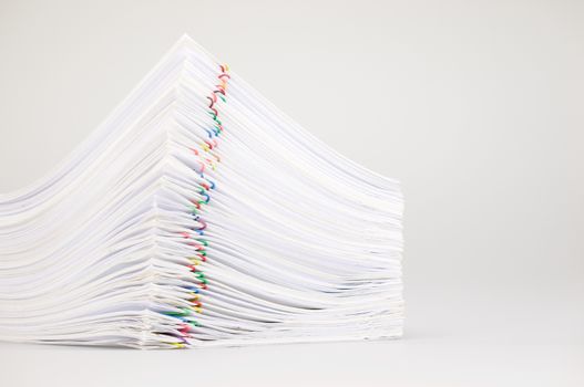 Pile overload paperwork of receipt and report with colorful paperclip place on white background.