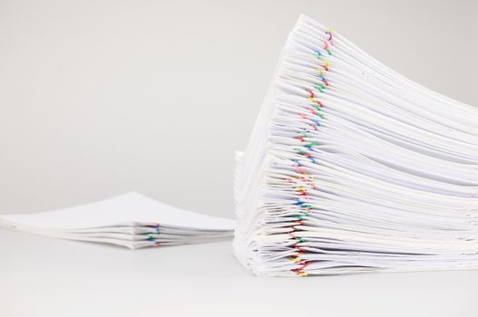 Pile overload paperwork of receipt and report with colorful paperclip with blur pile document place on white background.