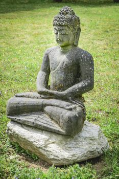 Image of a stone buddha on a green meadow