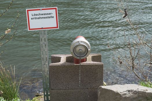 Information board with the inscription in German fire water extraction point. Firefighting Equipment in a river.