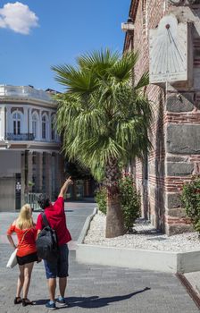 Couple tourists looking at sun clock on the corner of Dzhuaya, Djumaya Mosque or Cuma Camii in turkish, downtown Plovdiv on a sunny summer day.