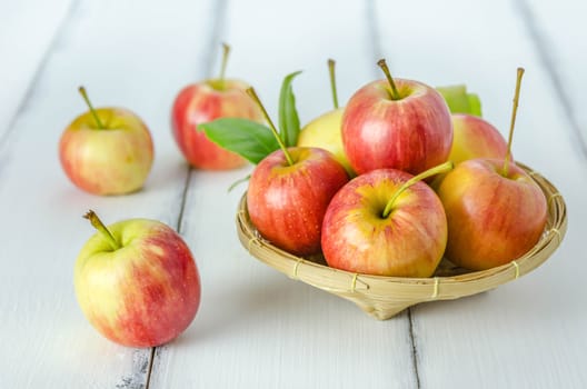 Red and yellow apple  with bamboo basket , organic fresh fruit on white  wooden background