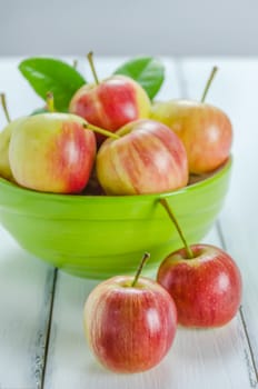 fresh red and yellow apple with green bowl on wooden background