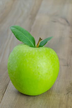 Ripe green apple with leaf  on a wooden background