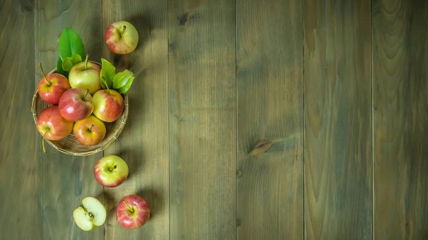 Top view red and yellow apple with leaves and  bamboo basket on wooden background with free space for text
