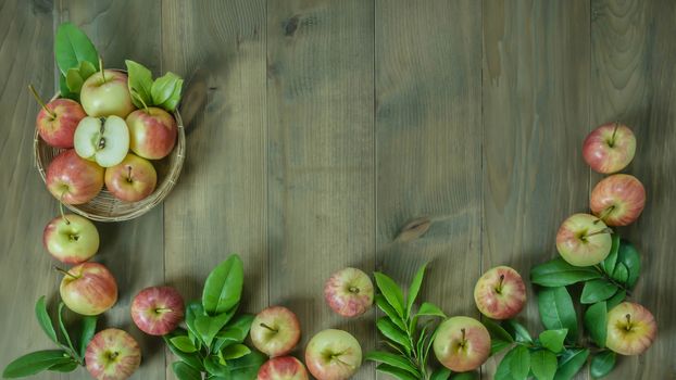 Top view red and yellow apple with leaves and  bamboo basket on wooden background with free space for text