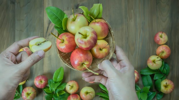 human hand holding red and yellow apple  on wooden background , Top view