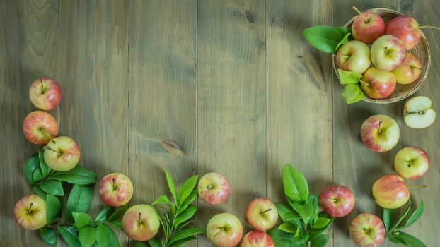 Top view red and yellow apple with leaves and  bamboo basket on wooden background with free space for text
