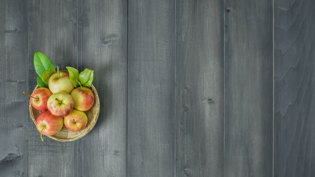 Top view red and yellow apple with leaves and  bamboo basket on wooden background with free space for text