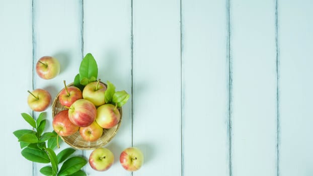 Top view red and yellow apple with leaves and  bamboo basket on  white wooden background with free space for text