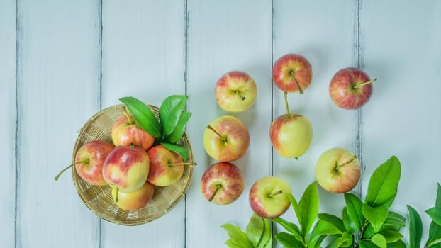 Top view red and yellow apple with leaves and  bamboo basket on  white wooden background with free space for text