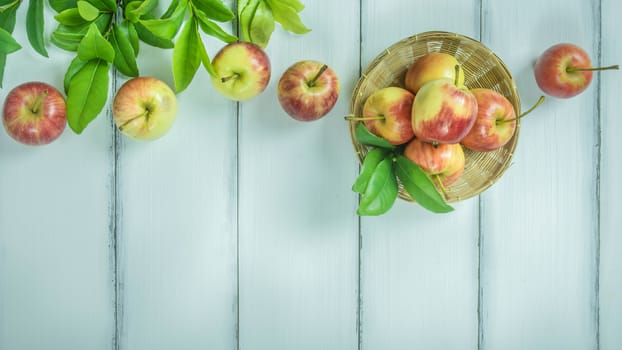 Top view red and yellow apple with leaves and  bamboo basket on  white wooden background with free space for text