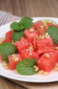 A refreshing salad of watermelon cubes with slices of lime, mint, peanuts, pine nuts