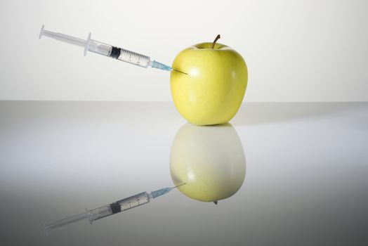 The syringe with the needle thrust in green beautiful apple