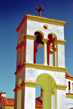 A bell tower of monastery of white and orange colors.