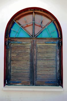 A wooden window with shutters and stained-glass windows.