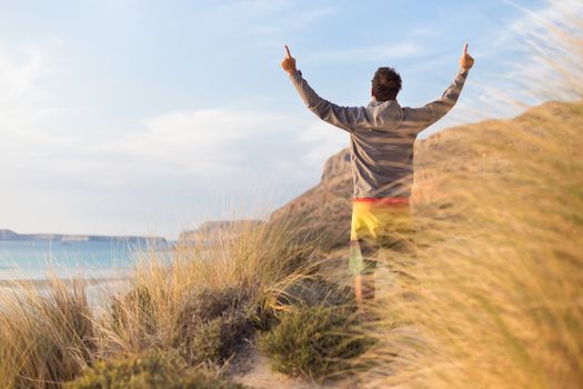 Sporty active man, arms raised, enjoying beauty of nature, freedom and life at beautiful landscape. Active lifestyle outdoors. Made it.