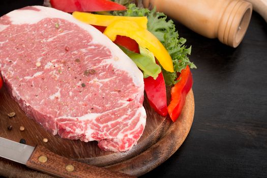 raw pork steak with vegetables on wooden background