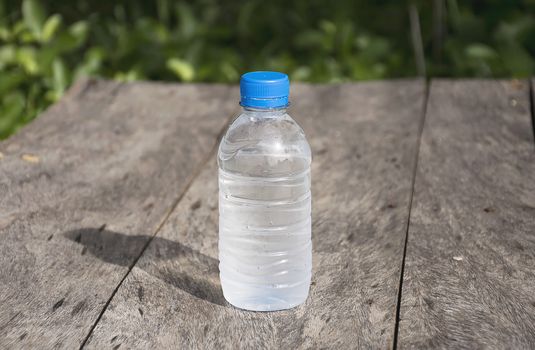 Water bottle on wood table with nature background. Fresh and energy concept.