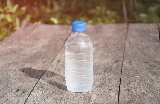 Water bottle on wood table with nature background. Fresh and energy concept.