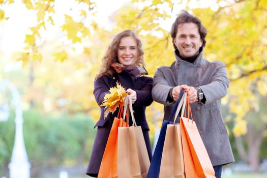 Happy couple with shopping bags in autumn park