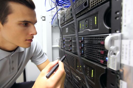 Young engeneer man in network server room connecting wires