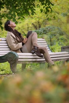 Woman using digital tablet sitting in autumn park