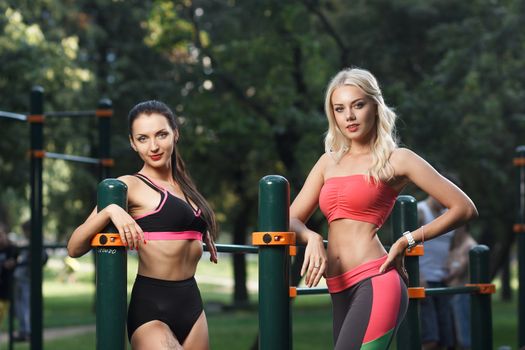 Concept: sport, healthy lifestyle. Young strong girls do exercises during street workout