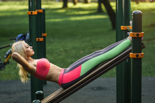 Concept: sport, healthy lifestyle. Young strong girl do exercises during street workout