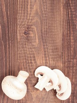 Fresh white champignon mushrooms close up on dark brown wooden background with copyspace. Flat lay or top view